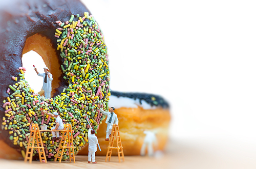 Group of painters painting over huge donut. Macro photo