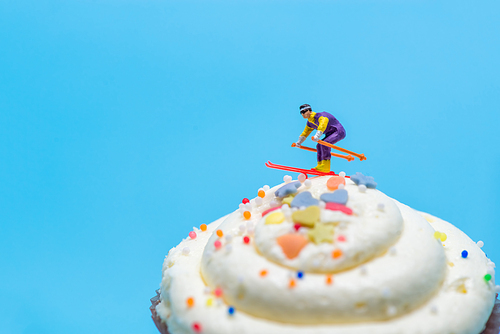 Miniature skier skiing down a cupcake.