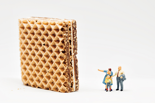 Miniature people. Two adults showing giant waffle to a boy