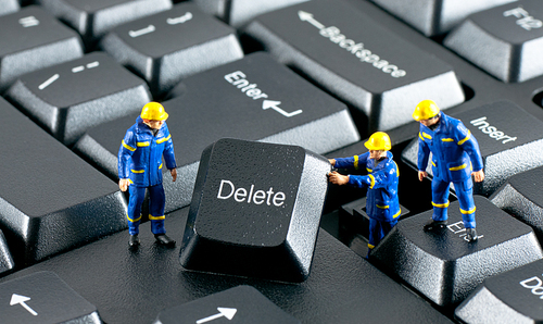 Team of construction workers working with DELETE button on a computer keyboard