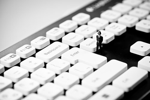 Miniature Police officer on top of computer keyboard. Internet piracy and criminality cpncept.
