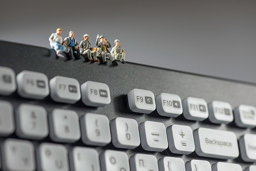 Miniature workers sitting on top of keyboard. Technology concept. Macro photo