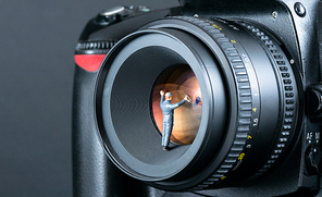 Miniature man cleaning camera lens. Macro photo