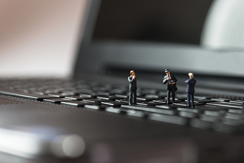 Miniature business people standing on laptop keyboard