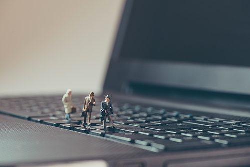 Miniature businessmen walking over the laptop