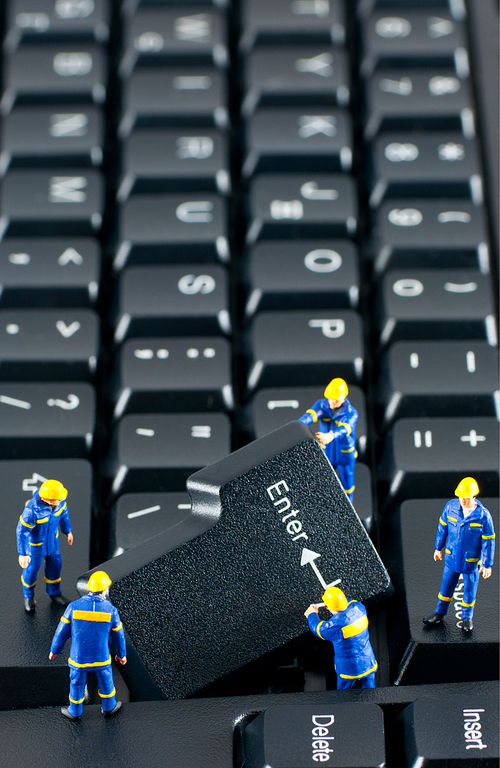 Team of construction workers working with ENTER button on a computer keyboard