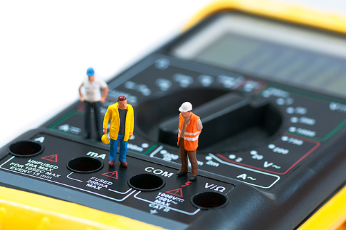 Miniature workers on top of multimeter. Macro photo