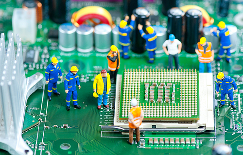 Group of miniature engineers inspecting computer processor