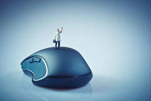 Miniature businessman waving on top of computer mouse. Business concept. Macro photo