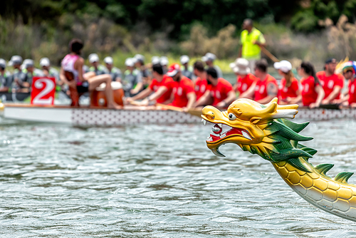 Dragon boat's head with racing team on the background
