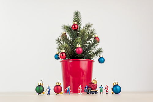 Miniature people decorating giant Christmas tree.