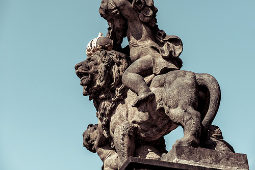 Statue of lion wearing a golden crown and two annoying him little guys on the gates of the First Courtyard, western side of Castle Square (Hradcanskй nбmestн) of Prague Castle. Czech Republic