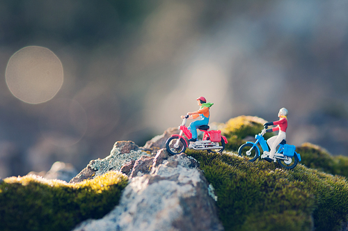 Miniature couple traveling through the countryside on vintage motorcycles at dawn. Macro photography