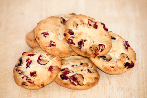 Heap of cranberry cookies on wooden plate. Close up