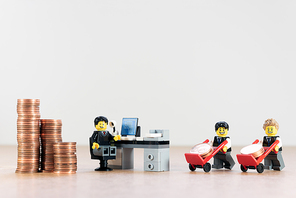 Businessmen pushing a hand truck with coins. Illustrative editorial. October 04, 2021