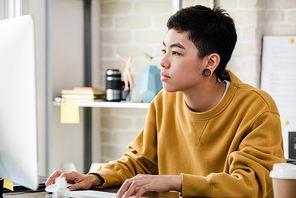 Young Asian tomboy woman in casual attire working from home in living room