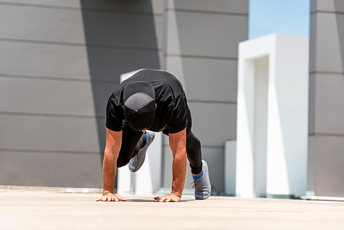 Fit sports man doing mountain climber exercise outdoors on building rooftop floor in sunlight