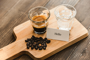Fresh brewed black Espresso coffee and water in shot glasses served on wooden platter ready to drink