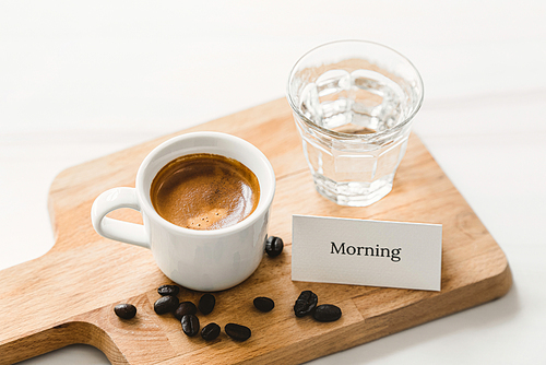 Fresh cup of brewed espresso coffee shot served for breakfast on wooden platter with good morning greeting card