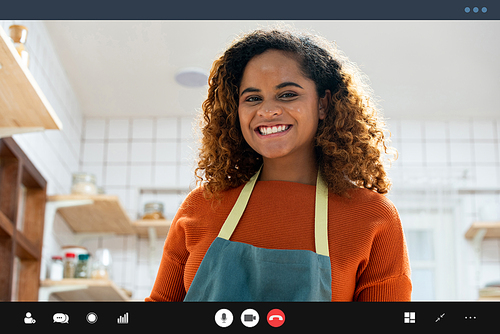 Happy smiling young African American woman having video call while cooking in kitchen at home