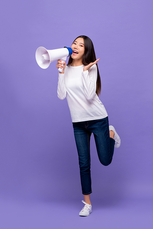 Full body of  beautiful Asian woman announcing on magaphone isolated on purple background