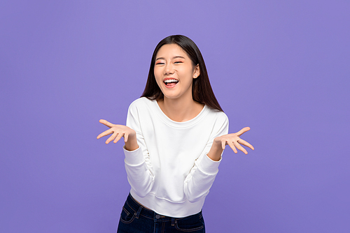 Smiling cheerful cute Asian woman in casual attire doing blowing kiss gesture with open palms isolated on purple studio background