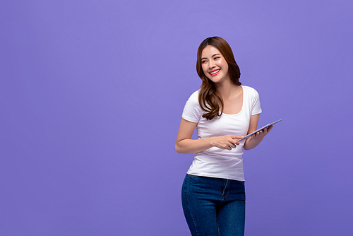 Portrait of smiling beautiful woman with digital tablet looking at empty space aside on colorful purple background