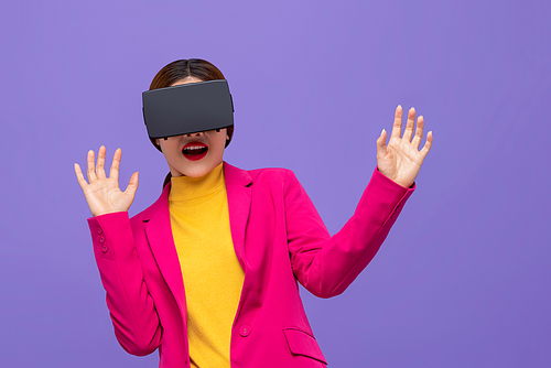 Shocked woman in colorful attire watching 3D simulation video from virtual reality or VR glasses on purple background