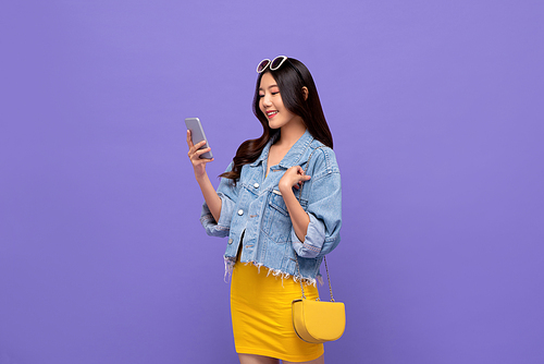 Portrait of smiling young pretty Asian woman having video call on mobile phone in isolated studio purple background
