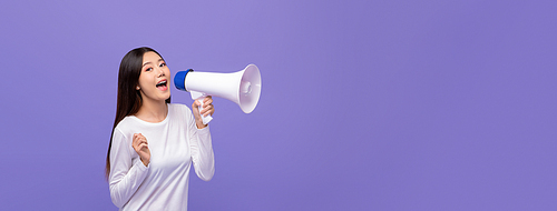 Cheerful cute Asian woman talking on magaphone isolated on purple banner background