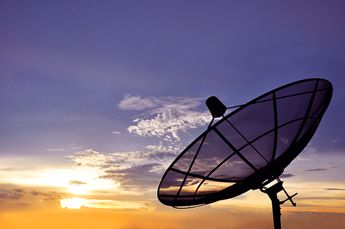 A black satellite dish on twilight sky background