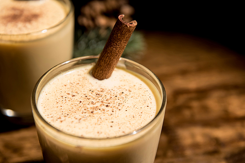 Close up of homemade traditional Christmas eggnog drinks with ground nutmeg, cinnamon, preparing for celebrating festive holiday season