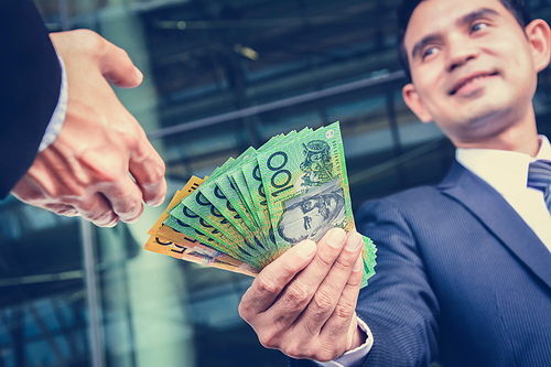 Businessmen passing money, Australia dollar (AUD) banknotes