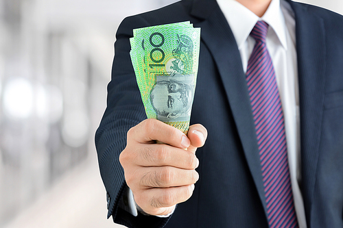 Businessman hand holding money, Australian dollar (AUD) banknotes - financial, investment success and profitable business concepts