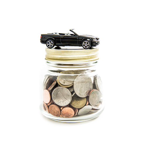 Toy car on the glass jar full of money (coins) - auto financial concept