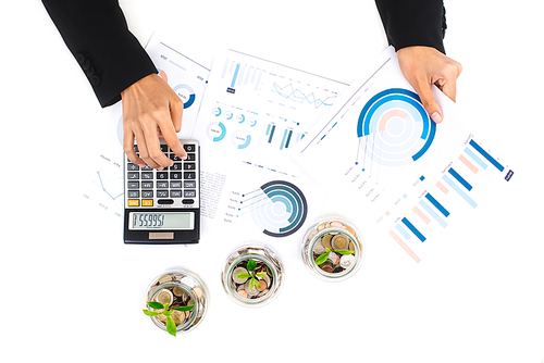 Woman working at work table with some documents and plants growing from coin (money) in the glass jars, financial analysis and investment concepts, top view