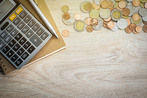 Money (coins), calculator and some stationery on wood table, top view with copy space - financial background concept