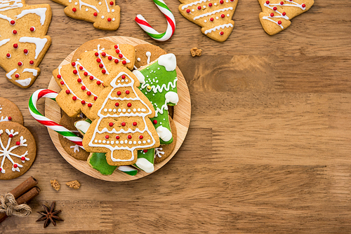 Assorted decorated Christmas gingerbread cookies on wood background, top view border design with copy space
