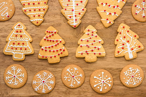 Festive decorated Christmas gingerbread cookies on wood background, top view