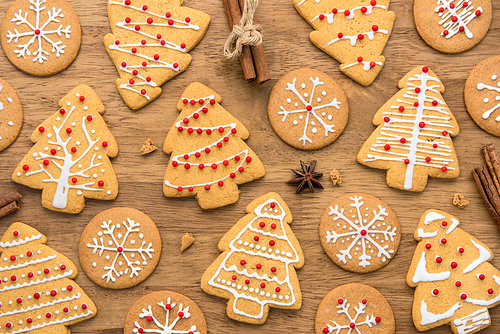 Festive decorated Christmas gingerbread cookies on wood background, top view