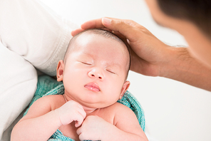 Father hand touching head of sleeping baby with care