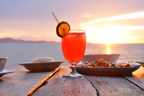 Cocktail drink with some Asian foods on old wooden table & sea water background