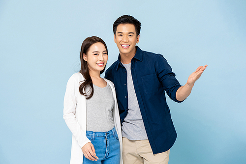 Lovely young happy smiling Asian couple in casual clothes on light blue isolated studio background
