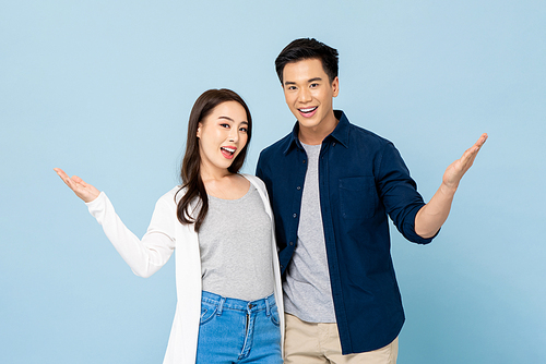 Happy smiling Asian couple doing open hand gesture in light blue isolated studio background