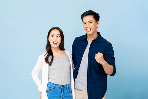 Portrait of smiling cheerful Asian couple on isolated light blue studio background