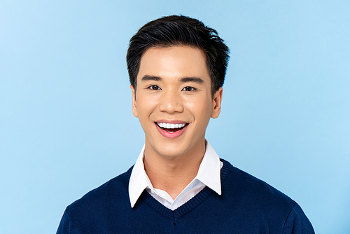 Close up portrait of young handsome smiling Asian man face on light blue studio background