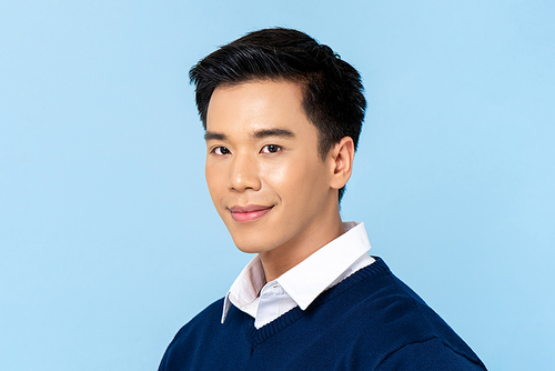 Close up portrait of young handsome Asian man face on light blue studio background