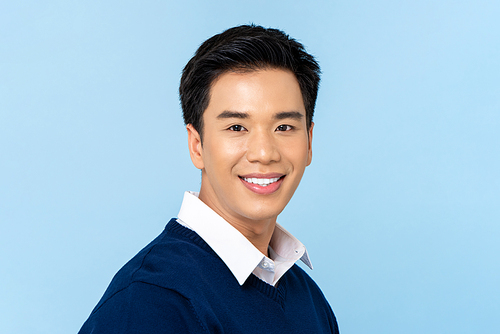 Close up portrait of young handsome smiling Asian man face on light blue studio background