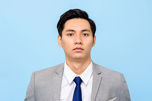 Close up portrait of serious young Asian businessman  in isolated studio blue background