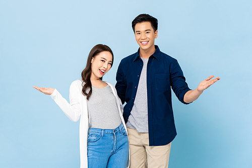 Announcement portrait of happy cheerful awesome Asian couple with big smiles opening hands on isolated light blue background